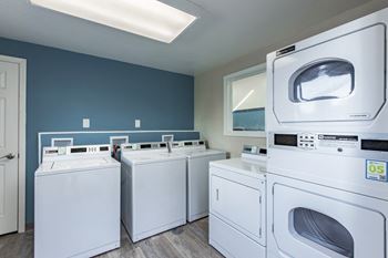 a row of washes and dryers in a laundry room  at The Lakes Apartments, Moses Lake, Washington